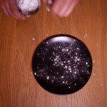 Dark Vador extraordinairement chocolat (Star Wars) - Saupoudrer l’assiette de dressage de sucre glace à l'aide d'une passette pour représenter les étoiles dans l’univers. (Photo : Elodie Davis).